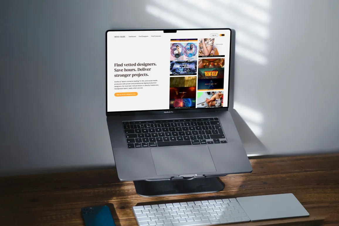 Laptop sitting on a desktop stand, showing the Smiths & Tailors homepage